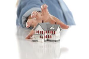 Womans Hand Reaching for Model House on White photo