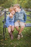 feliz joven hermano y hermana sentados juntos afuera foto