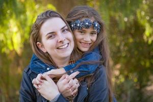 Madre caucásica cariñosa y retrato de hija de raza mixta al aire libre foto