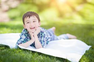 Mixed Race Chinese and Caucasian Young Boy Relaxing Outside On The Grass photo