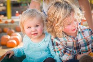 un dulce niño juega con su hermanita en un rancho rústico en el huerto de calabazas. foto