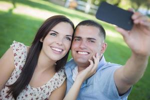 Mixed Race Couple Taking Self Portrait in Park photo