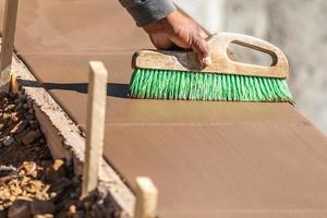 Construction Worker Using Brush On Wet Cement Forming Coping Around New Pool photo