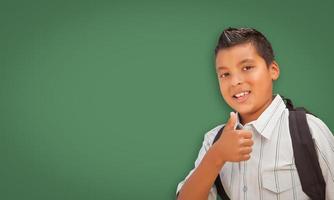 lindo niño hispano frente a una pizarra en blanco foto