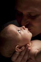 padre joven sosteniendo a su bebé recién nacido de raza mixta foto