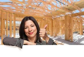 Hispanic Woman With Thumbs Up On Site Inside New Home Construction Framing. photo