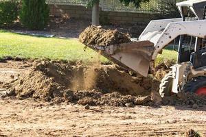 Small Bulldozer Digging In Yard For Pool Installation photo