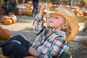 niño pequeño con sombrero de vaquero en el huerto de calabazas foto