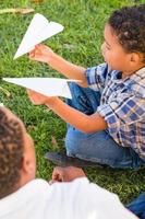 Happy African American Father and Mixed Race Son Playing with Paper Airplanes in the Park photo