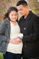 Hispanic Pregnant Couple Holding Baby Shoes photo