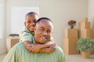 padre e hijo afroamericanos en la habitación con cajas de mudanza llenas foto