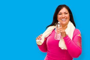 Middle Aged Hispanic Woman In Workout Clothes With Towel and Water Bottle Against A Cyan Blue Background photo