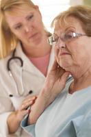 mujer adulta mayor siendo consolada por una doctora o enfermera foto