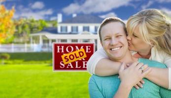 Happy Couple In Front Sold Real Estate Sign and House photo
