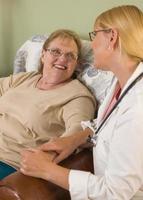 Doctor or Nurse Talking to Sitting Senior Woman photo