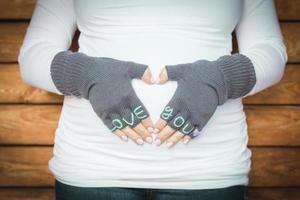 Pregnant Woman Holds Her Stomach with Love You Mittens photo