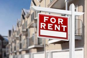 For Rent Real Estate Sign In Front of a Row of Apartment Condominiums Balconies and Garage Doors. photo