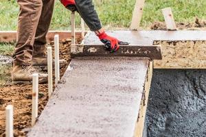 Construction Worker Leveling Wet Cement Into Wood Framing photo