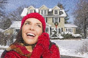 sonriente mujer de raza mixta en ropa de invierno afuera en la nieve foto