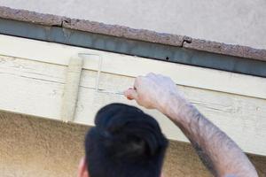 pintor profesional que usa un rodillo pequeño para pintar la fascia de la casa foto