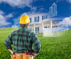 Contractor Standing Outdoors Looking Over Grass Site with Ghosted House. photo