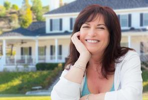 Attractive Middle Aged Woman Relaxing In Front Yard of Beautiful House photo