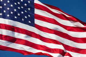 bandera estadounidense ondeando en el viento contra un cielo azul profundo foto