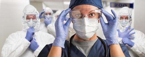 Team of Female and Male Doctors or Nurses Wearing Personal Protective Equiment In Hospital Hallway photo