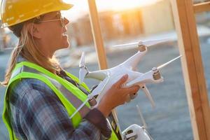 Sistema de aeronaves no tripuladas hembra piloto de drones quadcopter sosteniendo drones en el sitio de construcción foto