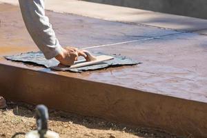 Construction Worker Applying Pressure to Texture Template On Wet Cement photo