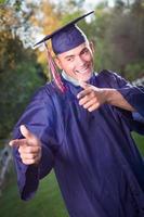 feliz guapo graduado masculino en toga y birrete afuera. foto