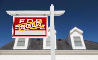 Left Facing Sold For Sale Real Estate Sign In Front of House and Deep Blue Sky. photo