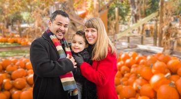 feliz familia birracial divirtiéndose en la granja de calabazas. foto