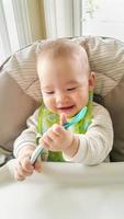 Adorable Chinese and Caucasian Baby Boy Playing With His Spoon Sitting in High Chair photo