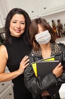 Young Hispanic Girl Student with Mother At Home Getting Ready For School Wearing Medical Face Mask photo