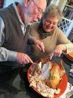 Senior Adult Couple Cutting the Holiday Turkey Together photo