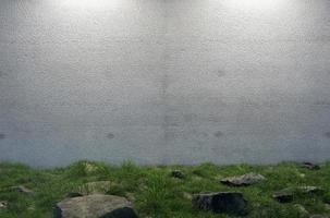 misteriosa pared de cemento en blanco rodeada de grandes rocas y hierba en el campo. foto