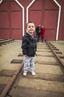 niño de raza mixta en la estación de tren con los padres sonriendo detrás foto