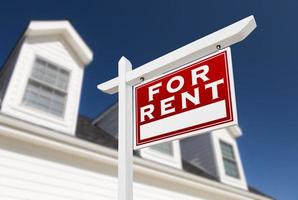 Right Facing For Rent Real Estate Sign In Front of House and Deep Blue Sky. photo