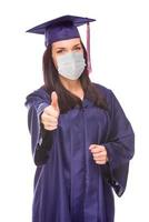 Graduating Female Wearing Medical Face Mask and Cap and Gown  Give a Thumbs Up Isolated on a White Background photo