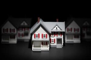 Several Model Houses In A Row With One Spot Lit In The Front photo