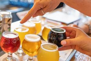 Female Hand Picking Up Glass of Micro Brew Beer From Variety on Tray photo