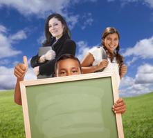 Young Students with Blank Chalk Board, Teacher Behind on Grass photo