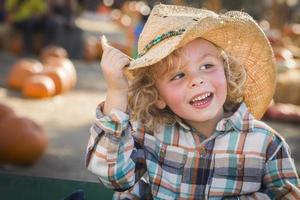 niño pequeño con sombrero de vaquero en el huerto de calabazas foto