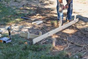 Worker Installing Stakes and Lumber Guides At Construction Site photo