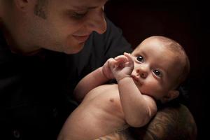 padre joven sosteniendo a su bebé recién nacido de raza mixta foto