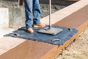 Construction Worker Applying Pressure to Texture Template On Wet Cement photo