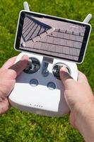 Hands Holding Drone Quadcopter Controller With Residential Roof Image on Screen photo