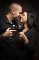 feliz pareja de raza mixta coqueteando y sosteniendo copas de vino foto