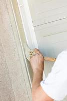 Professional Painter Cutting In With Brush to Paint Garage Door Frame photo